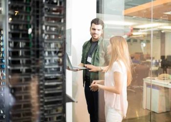 two-business-people-standing-server-room-with-laptop-discussing-1024x683